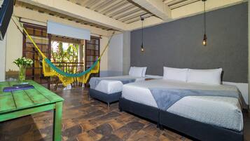 A room with two beds, a hammock, a table with a vase, and a ceiling fan.