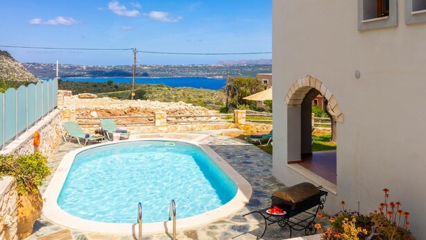 Una piscina con sillas de descanso, una parrilla y vistas al mar y las colinas.