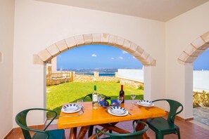 Une table dressée pour deux, avec vue sur la mer, une bouteille de vin et un verre de vin posés sur la table.