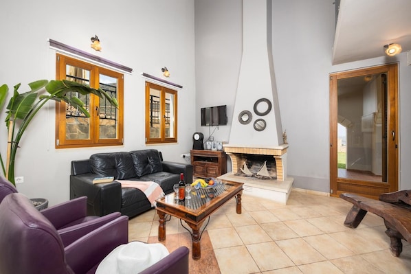 Ein Wohnzimmer mit Kamin, einer Couch, einem Couchtisch und einem Fernseher.