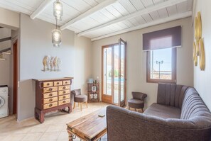 Un salón amplio con una mesa de centro de madera, un sofá y un armario con cajones. Hay una ventana con vistas al exterior y una puerta que da a otra habitación.
