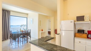 Una cocina moderna con encimera de mármol, un refrigerador, un microondas y un comedor con mesa y sillas.