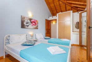 Ein Schlafzimmer mit zwei Betten, Holzbalkendecke, einem Gemälde und einem Kleiderschrank.