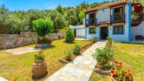 Una casa de dos pisos con un camino de piedra que lleva a la entrada, rodeada de un jardín bien cuidado con diversas plantas y flores.