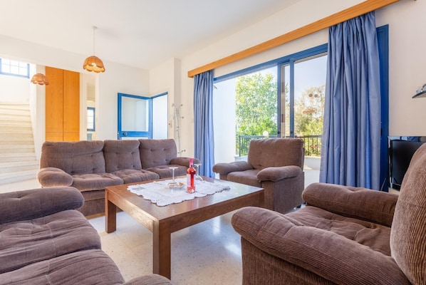 Amplia sala de estar con un conjunto de sofás, una mesa de centro y un televisor.
