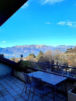 Un balcón con mesa y sillas, con vista a un paisaje montañoso.