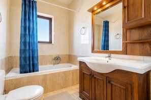 Une salle de bain avec une baignoire, des toilettes, un lavabo et des meubles en bois.