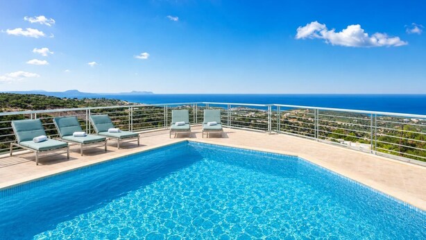 Une piscine avec des chaises longues, un ciel dégagé et une vue lointaine sur la mer.