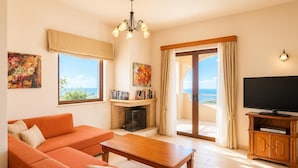 Un salon comprenant un canapé, une table basse, une cheminée, un téléviseur et un balcon avec vue.