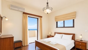 Une chambre d’hôtel avec un lit en bois, un bureau, une table de chevet, un luminaire au plafond, une fenêtre avec des rideaux et un appareil de climatisation.