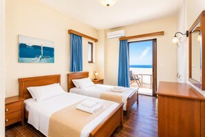 Une chambre d’hôtel avec deux lits, un bureau, une chaise, un tableau et une vue sur la plage.
