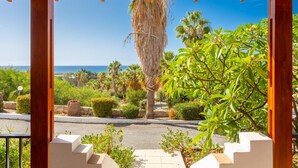 Un espacio al aire libre techado con vista a un jardín ajardinado y al mar.