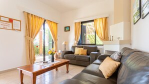 Una sala de estar con un sofá, una mesa de centro y una lámpara. Hay una ventana con cortinas y un cuadro en la pared.