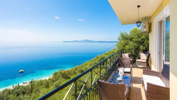 Een balkon met rieten meubilair en uitzicht op de kust.