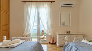 Een slaapkamer met twee bedden, een dressoir, een airconditioning en uitzicht op het landschap.