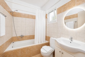 Ein Badezimmer mit Badewanne, Toilette, Waschbecken und Spiegel.