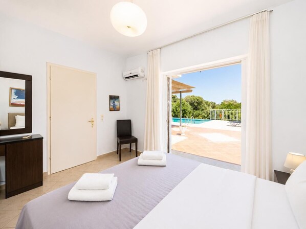 Ein Hotelzimmer mit Bett, Schreibtisch, Stuhl, Klimaanlage und Blick auf einen Außenpool.