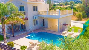 A two-story house with a swimming pool, a balcony, and a view of the surrounding landscape.