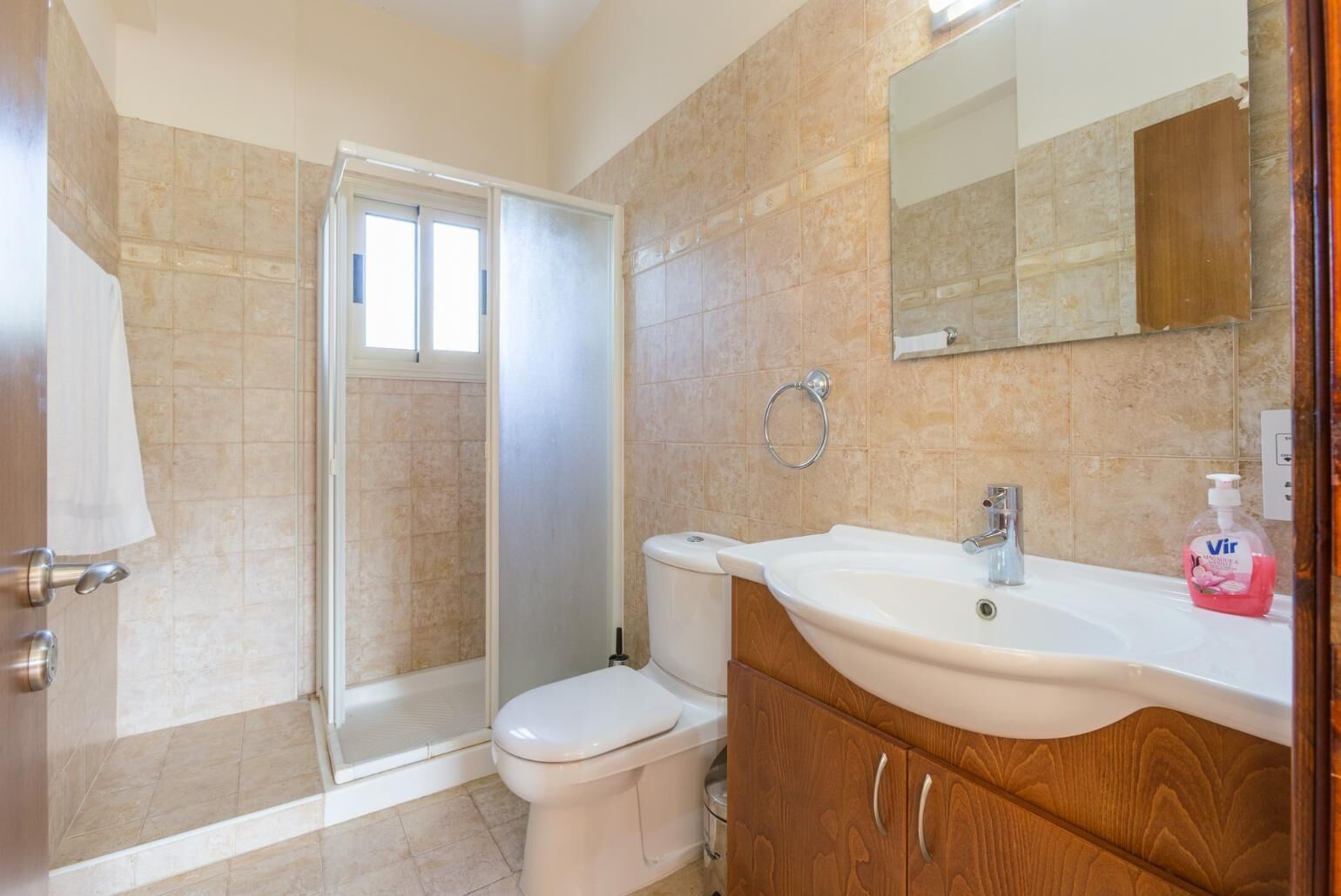 A bathroom with a shower, toilet, sink, and a mirror.