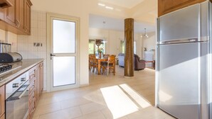 A spacious kitchen with a modern stainless steel refrigerator, wooden cabinets, and a dining area with a table and chairs.