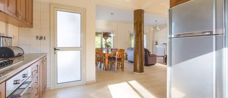 A spacious kitchen with a modern stainless steel refrigerator, wooden cabinets, and a dining area with a table and chairs.