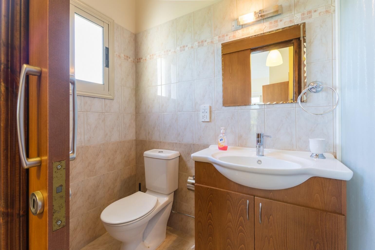 A bathroom with a toilet, sink, and mirror.