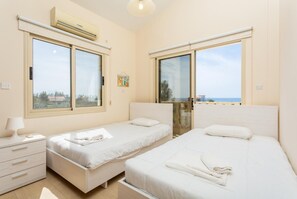 Un dormitorio con dos camas, una mesita de noche y una ventana.