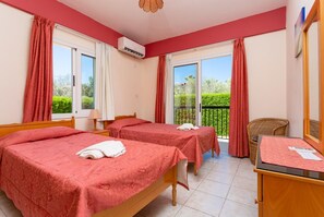Ein Hotelzimmer mit zwei Betten, einem Schreibtisch und einem Balkon mit roten Vorhängen.