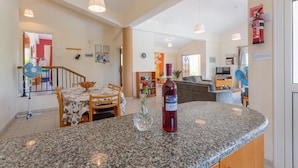 Eine moderne Küche mit Granit Arbeitsplatten, ein Essbereich mit Tisch und Stühlen sowie ein Wohnbereich mit Sofa und Fernseher.