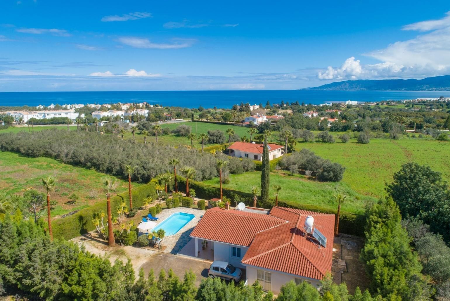 Une villa avec piscine, entourée d’une végétation luxuriante et offrant une vue sur la mer.