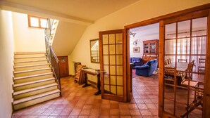 Ein geräumiger Wohnbereich mit Treppe, einem Esstisch mit Stühlen und einem blauen Sofa.