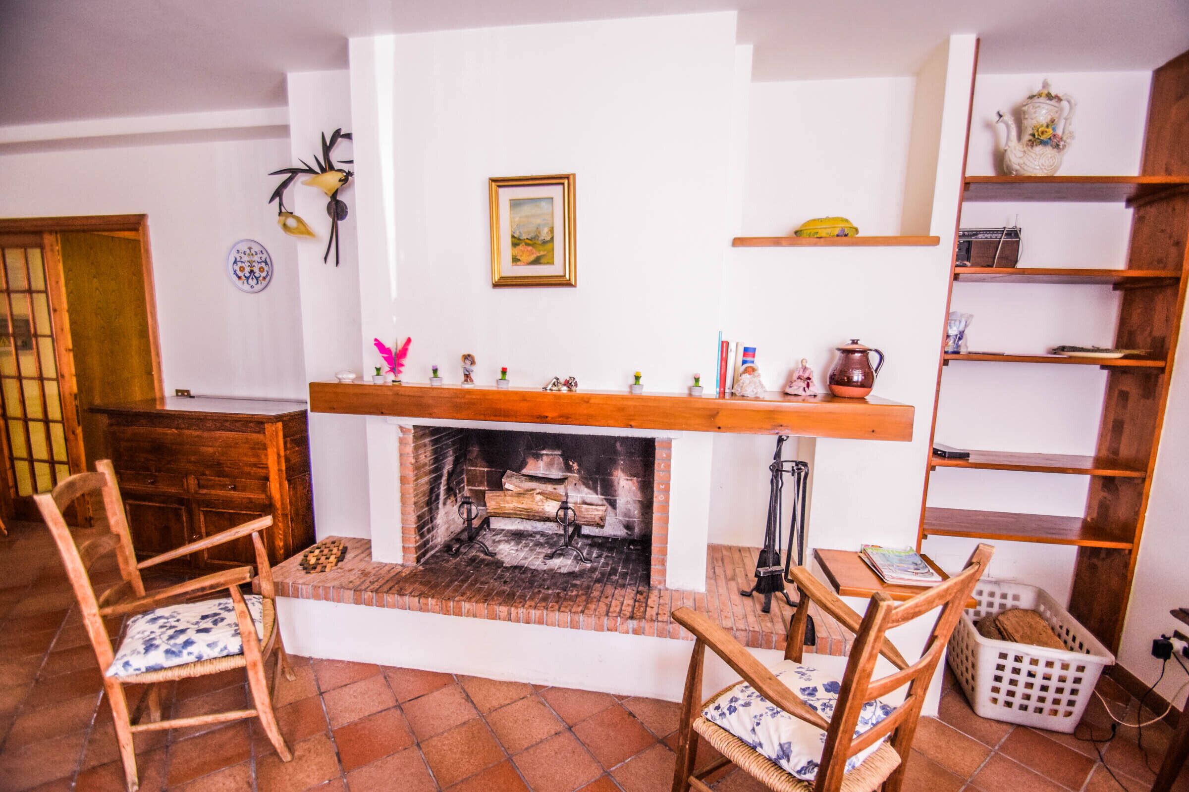 A cozy living room with a fireplace, wooden furniture, and a bookshelf.