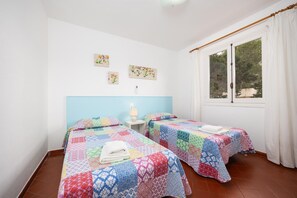 Une chambre avec deux lits, une fenêtre avec des rideaux et des œuvres d’art murales.