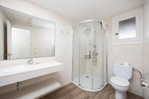 Ein modernes Badezimmer mit einer Duschkabine aus Glas, einem weißen Waschbecken und einer Toilette.