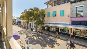 A street view with buildings, trees, and parked bicycles. - Duval's Duet - Double Balconies Duval Street (Key West)