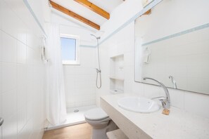 Une salle de bain avec des carreaux blancs, une douche, des toilettes, un lavabo et un miroir.