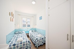 Une chambre avec deux lits, une fenêtre donnant sur un beau paysage et une porte.