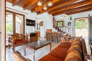 A spacious living area with wooden furniture, a flat-screen TV, and a kitchen in the background. - Villa Eva Large Private Pool, A/C, WiFi (Apokoronos)