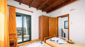 Een kamer met twee bedden, een houten kledingkast, een schuifglasdeur naar een balkon en een houten plafond.
