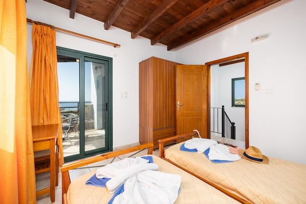 A room with two beds, a wooden wardrobe, a sliding glass door to a balcony, and a wooden ceiling. - Theo Beach Villa - Four Bedroom Villa, Sleeps 9 (Sfakia)