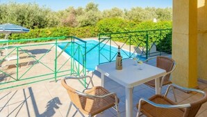 Un espacio al aire libre cubierto con piscina, una mesa con sillas y una botella de champán.