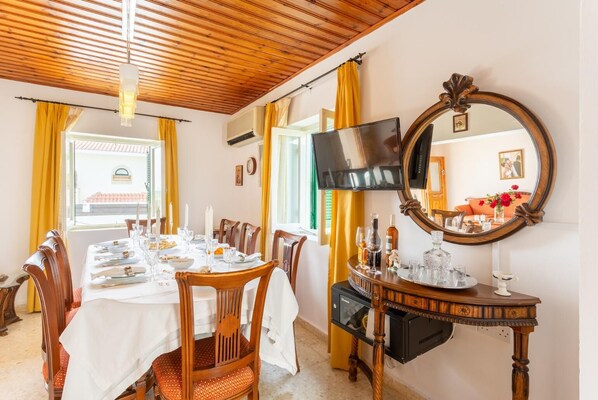 Un comedor con techo de madera, un televisor montado en la pared y un espejo grande.