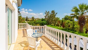 Un balcon avec une balustrade blanche, une table ronde et une chaise.