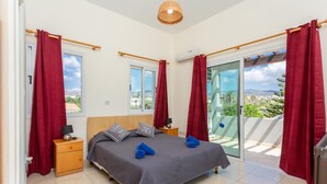 Une chambre à coucher avec un lit, deux tables de chevet, une fenêtre et un balcon avec des rideaux rouges.