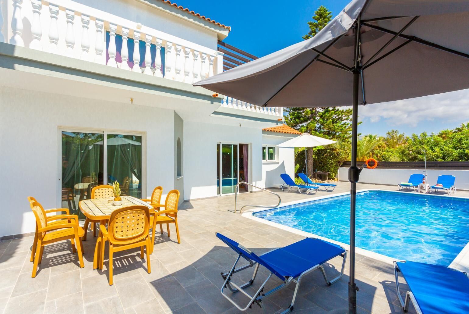Ein Poolbereich mit Tisch, Stühlen und Liegestühlen.