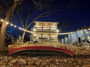 Un bâtiment à deux étages, doté de fondations en pierre, d’un espace extérieur couvert et de guirlandes lumineuses.