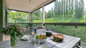 A dining table set with food and drinks on a deck with a view of a grassy field and trees. - Holiday Club Turun Caribia Superior Apartments (Turku)