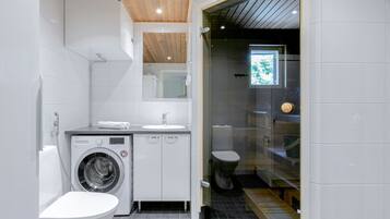 Ein kleines, modernes Badezimmer mit Waschmaschine, Toilette und Waschbecken.