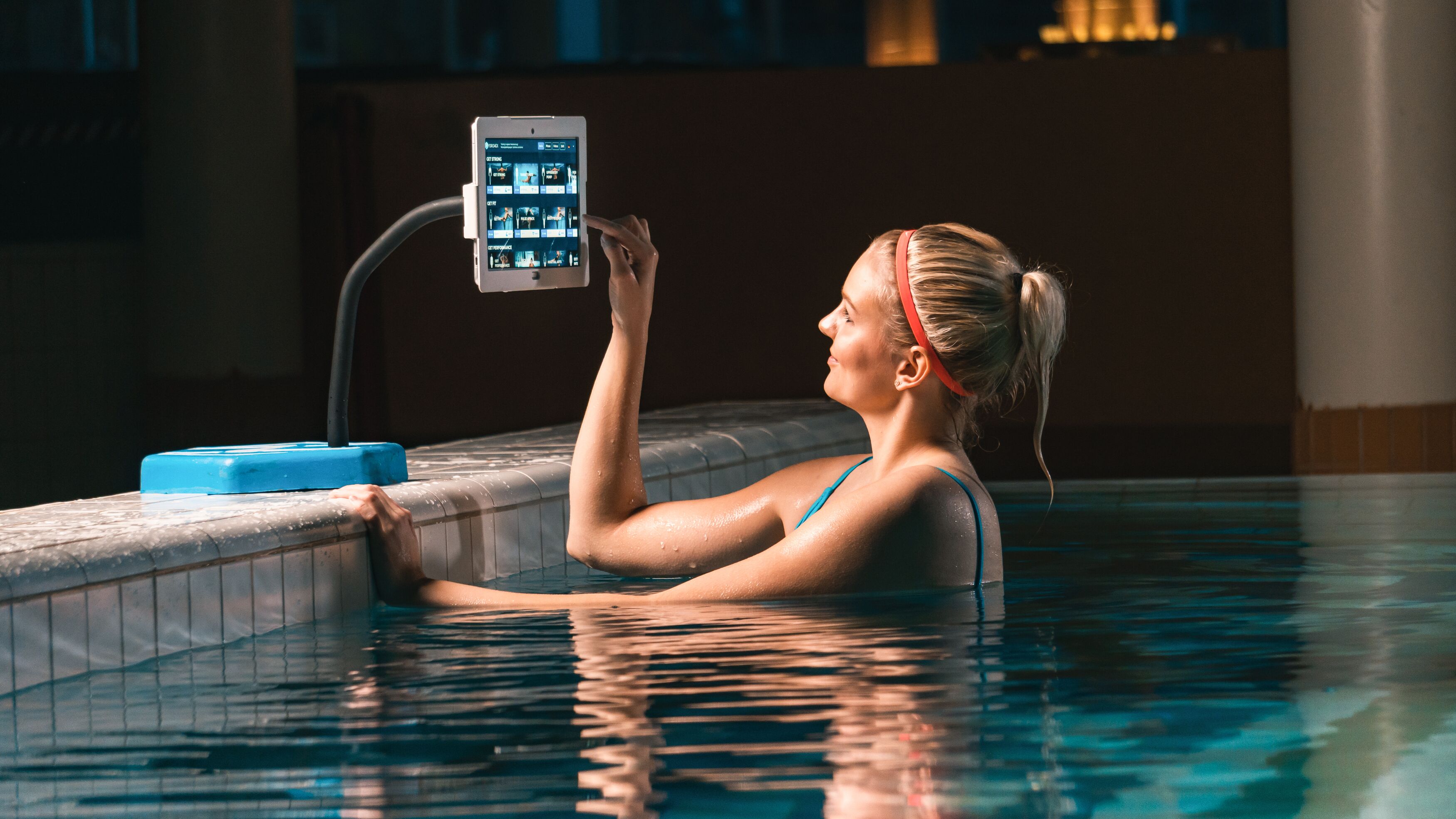 A person in a swimming pool using a tablet.