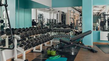Un gimnasio con racks para pesas, kettlebells y equipamiento de ejercicio.